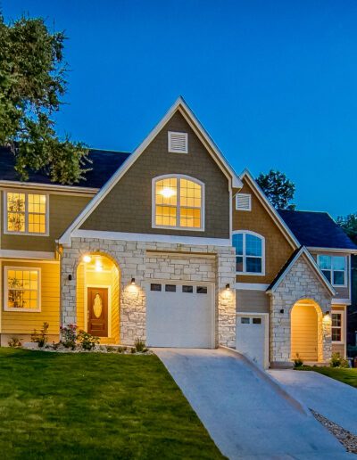 A two-story suburban home lit up during twilight with a well-manicured lawn.