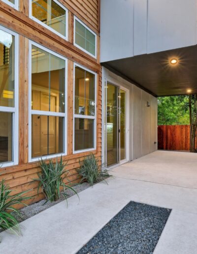 Modern house exterior with large windows and a covered walkway.